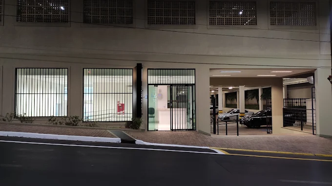 Fachada do Plantão Policial de Araraquara à noite, com janelas de grade e a garagem iluminada