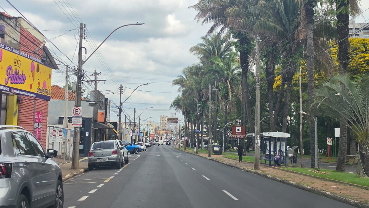 Céu com nuvens carregadas sobre uma rua de Araraquara, com calçadas, árvores e prédios baixos ao fundo, sob luz de fim de tarde.