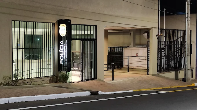 Fachada do Plantão Policial de Araraquara à noite, com a porta de grades fechada