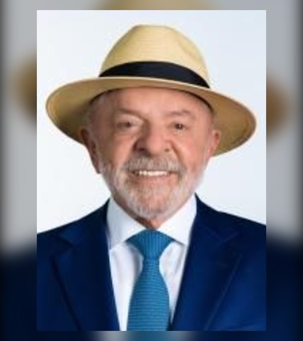 Foto oficial de Lula, de chapéu claro, terno azul e gravata azul, sorrindo