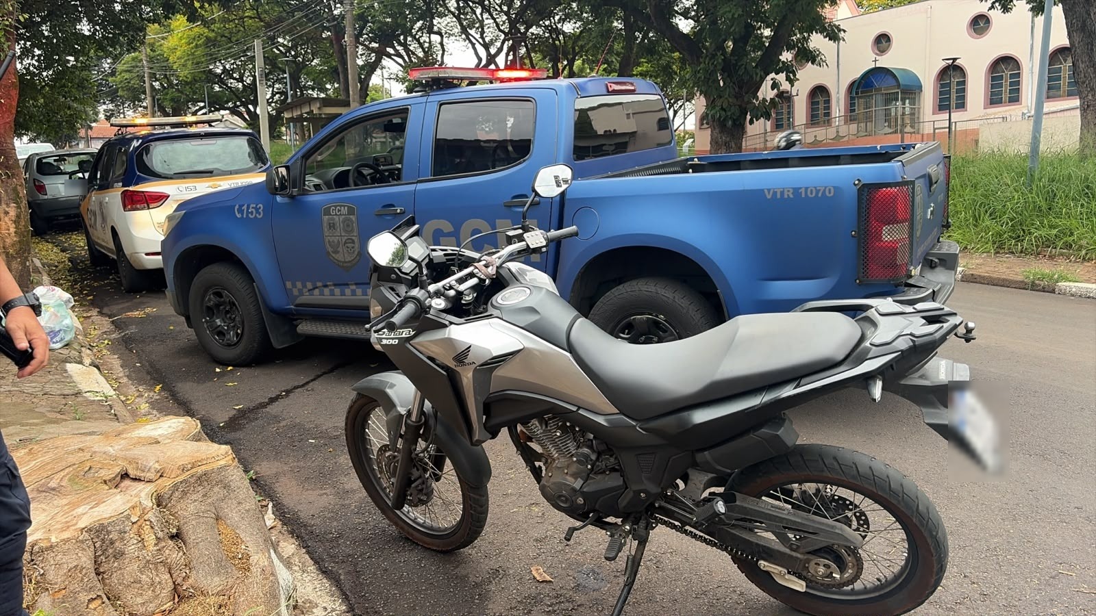 Moto prata estacionada na rua ao lado de duas viaturas da Guarda Civil Municipal de Araraquara