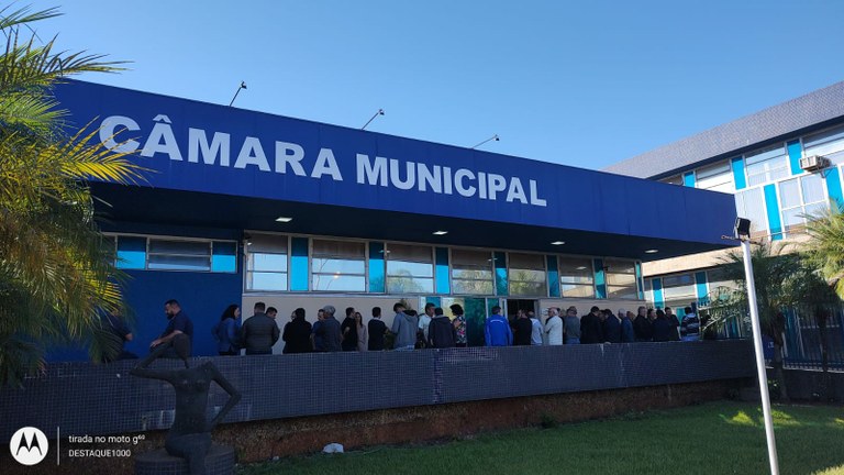 Fachada azul da Câmara Municipal de Américo Brasiliense, com pessoas em fila na entrada