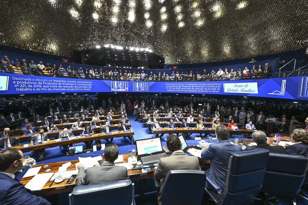 Plenário do Senado cheio, com senadores nas bancadas e público nas galerias, e um telão sobre a escala 6x1