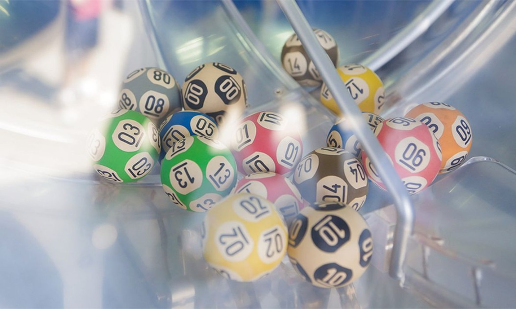 Bolas de loteria numeradas e coloridas girando em um globo de sorteio da Mega-Sena.