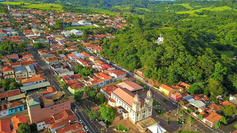 Foto de capa: vista de um céu limpo e azul sobre Ribeirão Bonito, com ruas, prédios baixos e árvores sob a luz do sol da manhã.